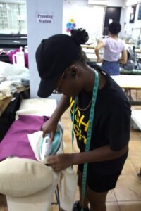 Avajae, Utech student, creating a jacket for her final assignment on December 4th, 2025 Girl in black with blue tape measurement ironing fabric